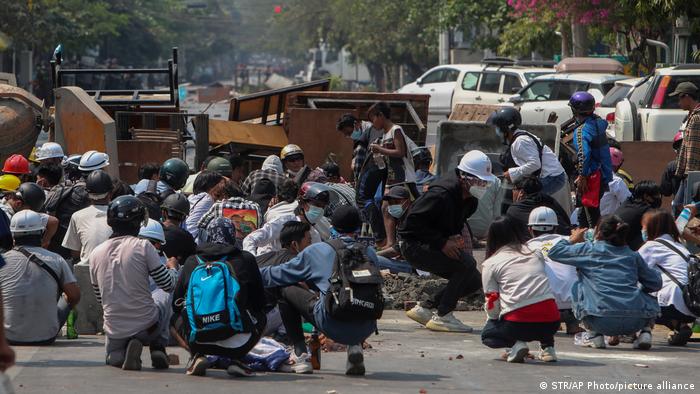 Anti-coup protesters take cover behind makeshift barricades in Mandalay, Myanmar