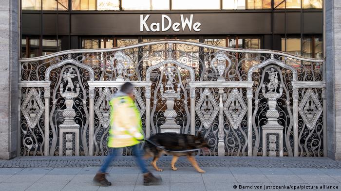 Охранник с собакой проходит мимо закрытых дверей магазина KaDeWe