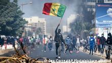 A demonstrator waves a Senegalese national flag during protests in support of main opposition leader and former presidential candidate Ousmane Sonko in Dakar, Senegal, Wednesday, March 3, 2021. Sonko was arrested Wednesday on charges of disturbing the public order after hundreds of his supporters clashed with police while he was heading to the court to face rape charges. (AP Photo/Leo Correa)