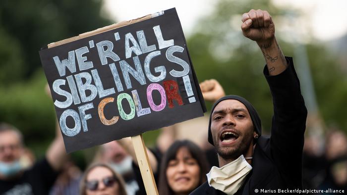 Un joven sosteniendo un cartel que dice Somos todos hermanos de colores