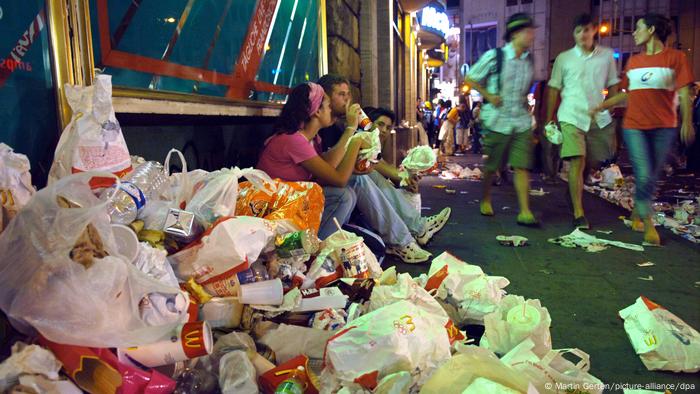 A pile of bafs and cartons from fast food restaruants litter the street