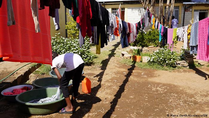 A young lady washes and hangs clothes outside.