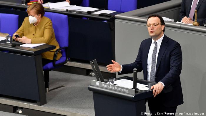 Jens Spahn govori u Bundestagu dok kancelarka klika na svom mobitelu.