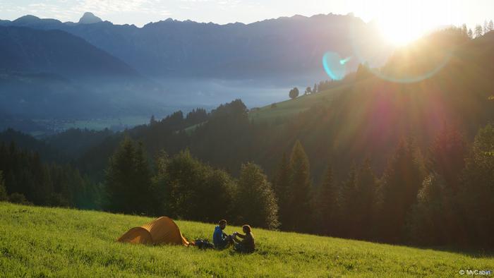 Una pareja acampa en una pradera en las montañas.