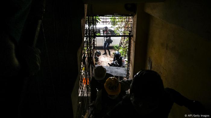 La policía persigue a un grupo de manifestantes por el pasillo de un edificio. Yangon