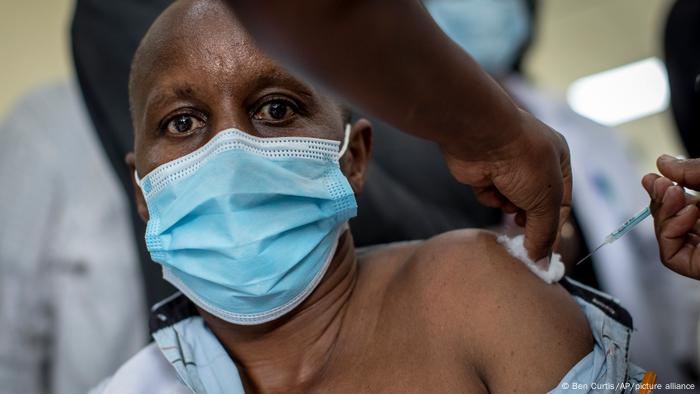 A Kenyan man in a mask receioving a vaccine