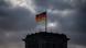 Reichstag tower with German flag against a dark cloudy sky Reichstag tower with German flag against a dark cloudy sky