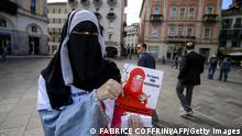 ARCHIV 18/09/2013 +++ Islamic Central Council of Switzerland (ICCS - CCIS) member Nora Illi, one of the few Swiss women wearing the niqab, poses on September 18, 2013 while distributing flyers reading Please don't lock me up in Lugano against an upcoming cantonal vote on banning face-covering headgear in public places. Ticino will become on September 22 the first Swiss canton to hold a so-called anti-burqa referendum. Although the initiative does not explicitly target Muslims--the phrasing to be voted on is nobody in public streets or squares may veil or hide their face--it is directed against the burqas and niqabs. Political commentators say the initiative has good chances of being accepted. AFP PHOTO / FABRICE COFFRINI (Photo credit should read FABRICE COFFRINI/AFP via Getty Images)