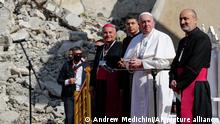 Pope Francis, surrounded by shells of destroyed churches, attends a prayer for the victims of war with Mosul and Aqra Archbishop Najib Mikhael Moussa, left, at Hosh al-Bieaa Church Square, in Mosul, Iraq, once the de-facto capital of IS, Sunday, March 7, 2021. The long 2014-2017 war to drive IS out left ransacked homes and charred or pulverized buildings around the north of Iraq, all sites Francis visited on Sunday. (AP Photo/Andrew Medichini)