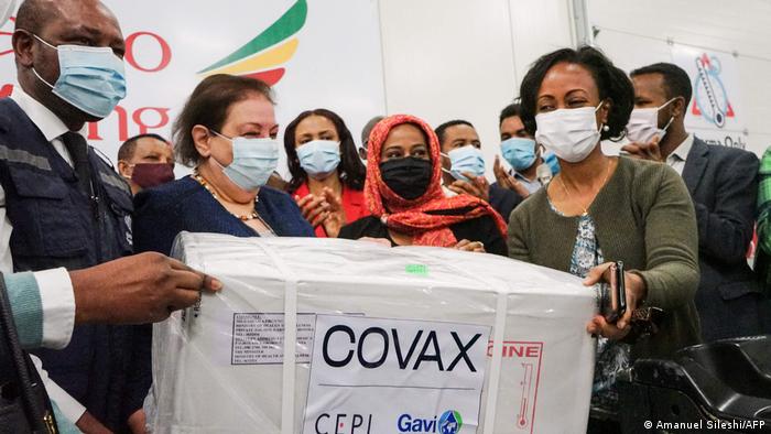 Empfänger mit Masken halten glücklich ein COVAX-Paket