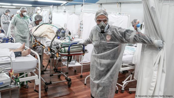 Profissionais de saúde conduzem um paciente numa maca num hospital de campanha montado num complexo esportivo em Santo André