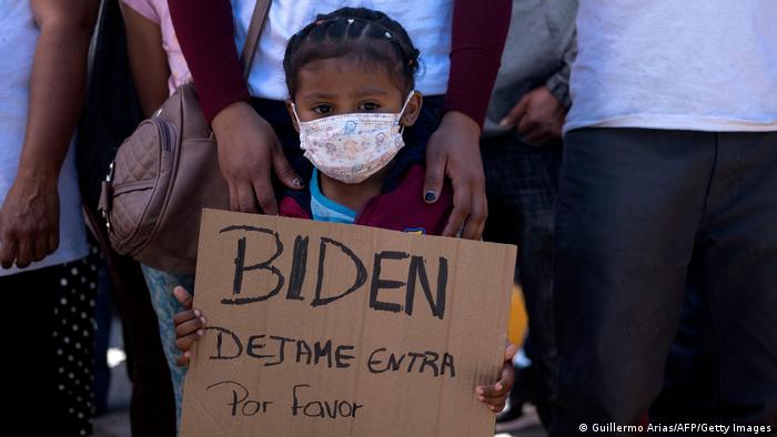 Asylsuchende aus Honduras hält Schild mit spanischsprachiger Aufschrift Biden, lass mich rein