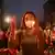 Woman holding a candle at a nighttime rally in Yangon