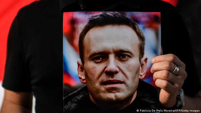 Мужчина держит портрет Алексея Навального на акции солидарности в Лиссабоне