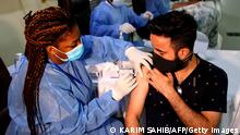 A healthcare worker administers a shot of China's Sinopharm COVID-19 vaccine to a man at the Guru Nanak Darbar Gurudwara (Sikh temple) in Dubai on February 28, 2021. (Photo by Karim SAHIB / AFP) (Photo by KARIM SAHIB/AFP via Getty Images)