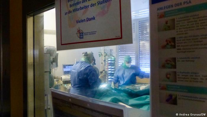 doctors seen through a screen as they operate on a patient