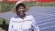 A woman in a hat stands in front of a solar panel A woman in a hat stands in front of a solar panel