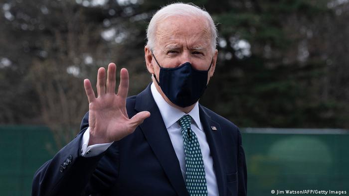 US President Joe Biden wears a mask and waves at reporters