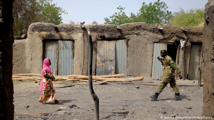 A soldier walks past a woman in Chad