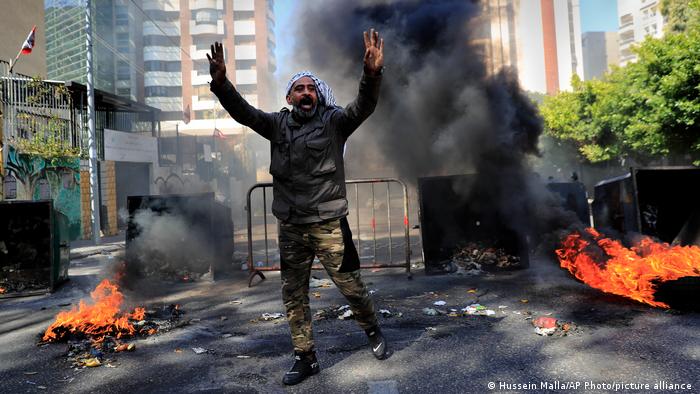 A man in front of burning tires and garbage containers during a protest in Lebanon