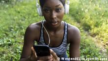 Young athlete in nature, listening music with headphones, holding smartphone model released Symbolfoto PUBLICATIONxINxGERxSUIxAUTxHUNxONLY GIOF04449 
