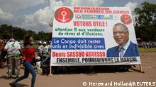 A woman runs past a poster in support of the re-election of the Republic of Congo's incumbent President and presidential candidate Denis Sassou Nguesso, in Brazzaville, Republic of Congo March 18, 2021. Picture taken March 18, 2021. REUTERS/Hereward Holland