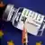 Seringa e frasco com dose da vacina da AstraZeneca em frente à bandeira da União Europeia.