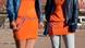 two women wearing orange dresses outside a stadium two women wearing orange dresses outside a stadium