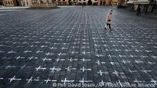 A woman walks at the Old Town Square in Prague, Czech Republic, Monday, March 22, 2021. A group of activists painted the crosses to criticize the government's response to the coronavirus pandemic. (AP Photo/Petr David Josek)