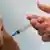 Profissional de saúde injeta vacina no braço de paciente.
