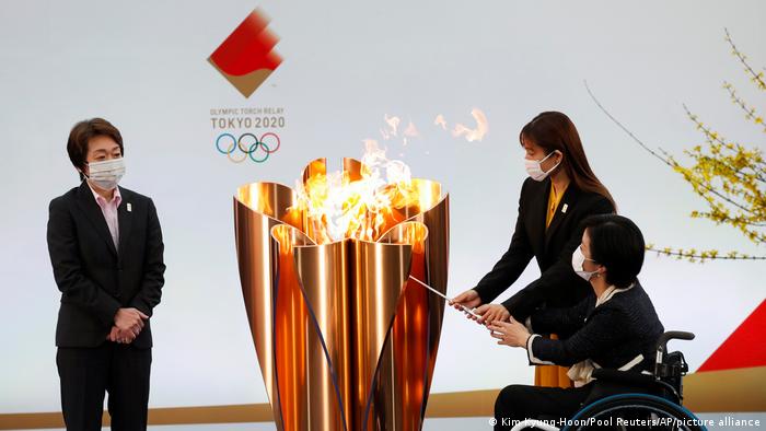 Seiko Hashimoto, left, watches Japanese actress Satomi Ishihara and Paralympian Aki Taguchi light the Olympic flame