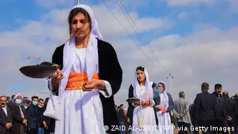 Women burn incense in a procession during a mass funeral for Yazidi victims of the Islamic State.