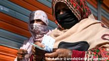A woman (R) counts rupee notes after collecting cash of financial assistance through a mobile wallet under the governmental Ehsaas Emergency Cash Programme for families in need during a government-imposed nationwide lockdown as a preventive measure against the COVID-19 coronavirus, in Islamabad on April 9, 2020. (Photo by Aamir QURESHI / AFP) (Photo by AAMIR QURESHI/AFP via Getty Images)