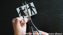 Family divorce. Cropped image of hand cutting paper family with scissors over wooden table.
