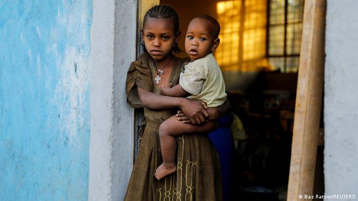 Asmara, 11, holds her 1-year-old brother Barakat at the doorway to a classroom now used as their living space, at the Tsehaye primary school, which was turned into a temporary shelter for people displaced by conflict