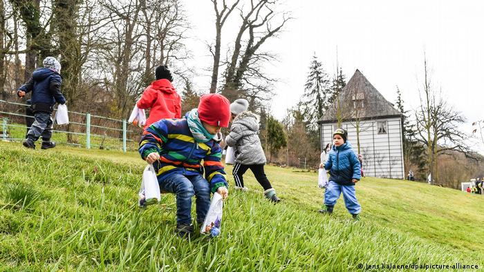 Children on a hillside meadow in Weimar embark on an Easter egg hunt.