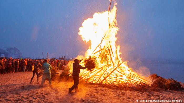 People on a river bank to gaze upon a big Easter bonfire in Hamburg