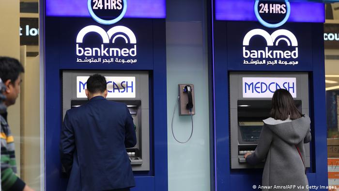 Lebanese men withdraw money from a Bankmed ATM in the capital, Beirut