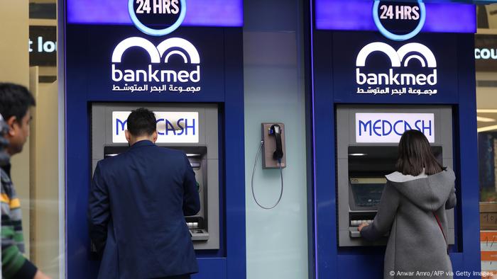 Lebanese men withdraw money from a Bankmed ATM in the capital, Beirut