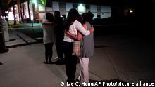 Unidentified people comfort each other as they stand near a business building where a shooting occurred in Orange, Calif., Wednesday, March 31, 2021. Police say several people were killed, including a child, and the suspected shooter was wounded by police. (AP Photo/Jae C. Hong)