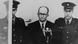 Adolf Eichmann (en el centro), escoltado por dos militares, frente al micrófono, durante su juicio en Israel. 12 de abril de 1961.