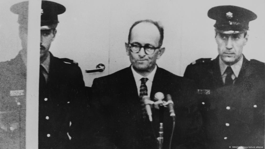 Adolf Eichmann (en el centro), escoltado por dos militares, frente al micrófono, durante su juicio en Israel. 12 de abril de 1961.