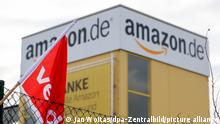 A view of the outside of the Amazon fulfillment center in Bad Hersfeld, Germany with a fence and the Verdi flag in the foreground