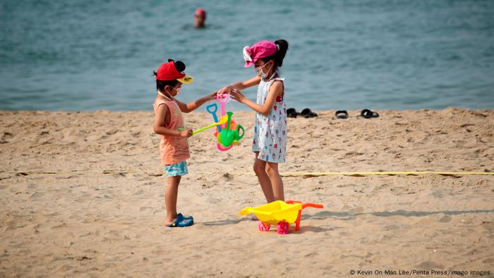 Children wearing surgical masks while playing at the Gold Coast Beach in Hong Kong