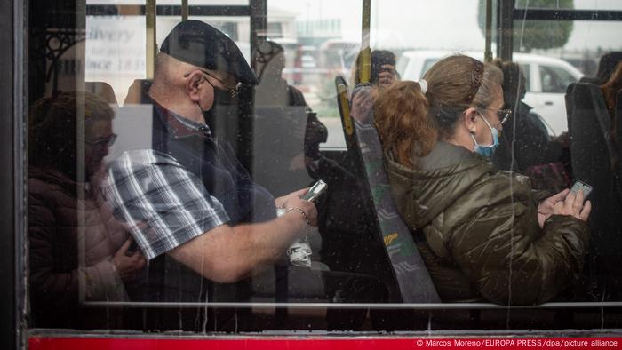 Personas sentadas en un autobús con máscaras.