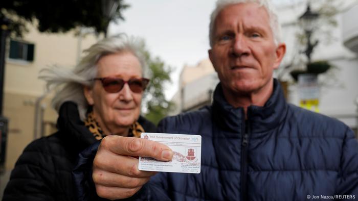 Un anciano se encuentra junto a su esposa, mostrando su registro de vacunación.