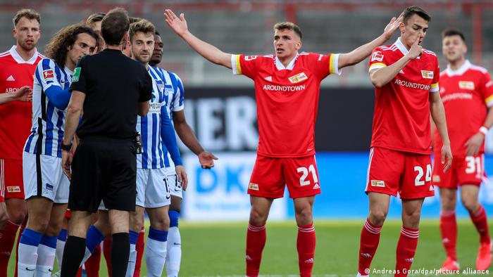 Ein Schiedsrichter spricht mit einem Fußballspieler. Ein Schiedsrichter spricht mit einem Fußballspieler.