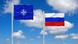 Флаги НАТО и России на фоне голубого неба Флаги НАТО и России на фоне голубого неба