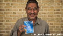 Afghan refugee Abdulrahim Rostami, 66, holds his health insurance booklet in Tehran, Iran.