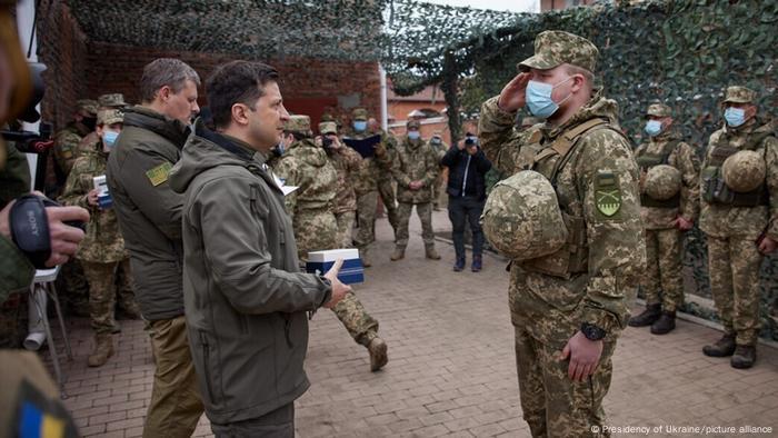 Ukrainian President Volodymyr Zelenskiy (left) salutes a soldier in Donbass, Ukraine